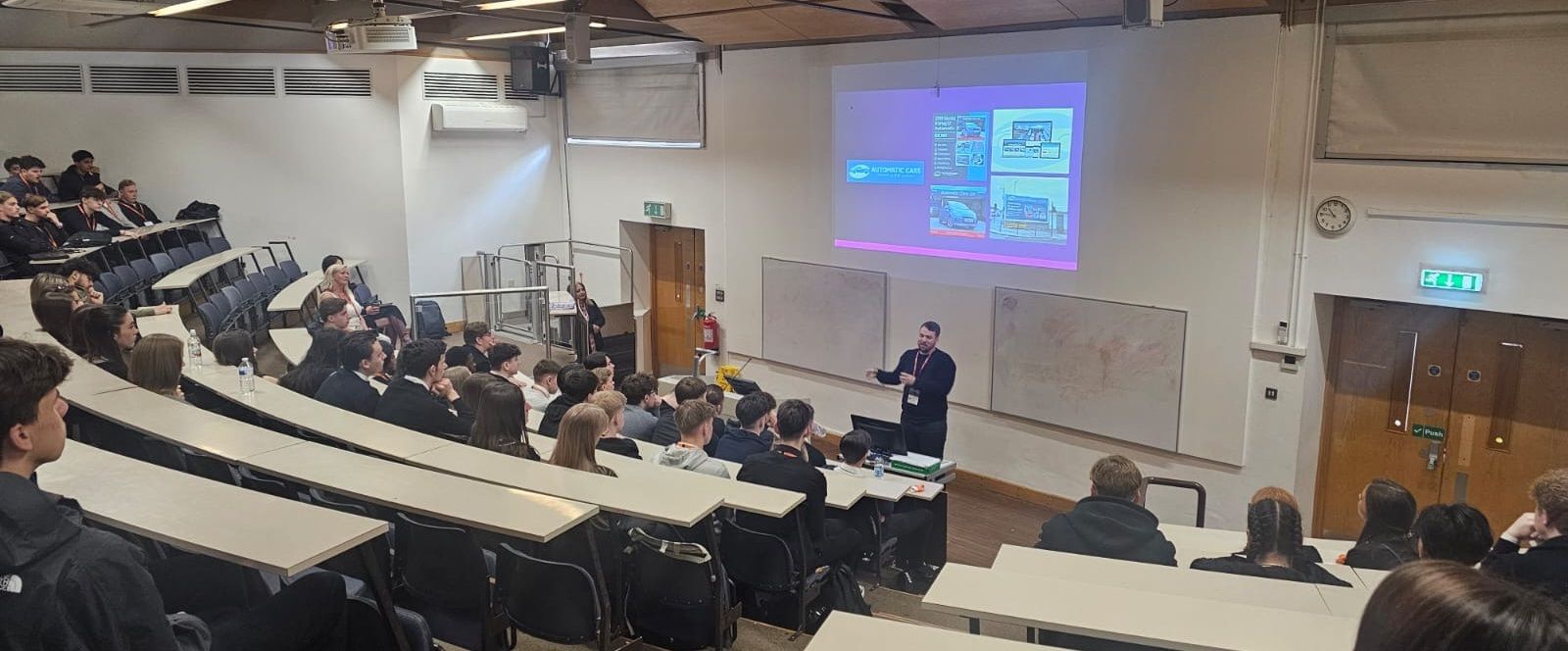 Person in lecture theatre talking to students