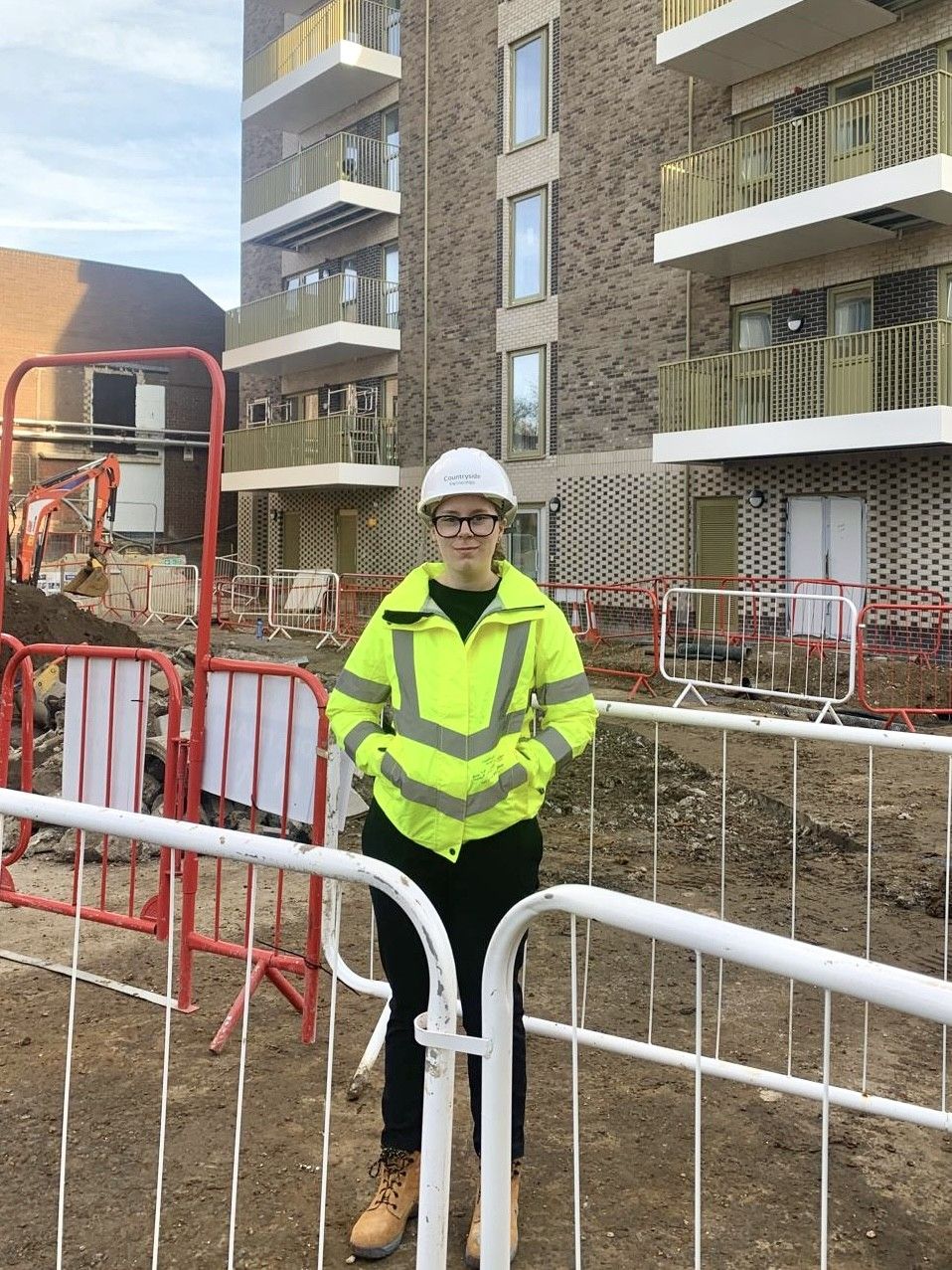 Construction student in hi-vis in front of construction site