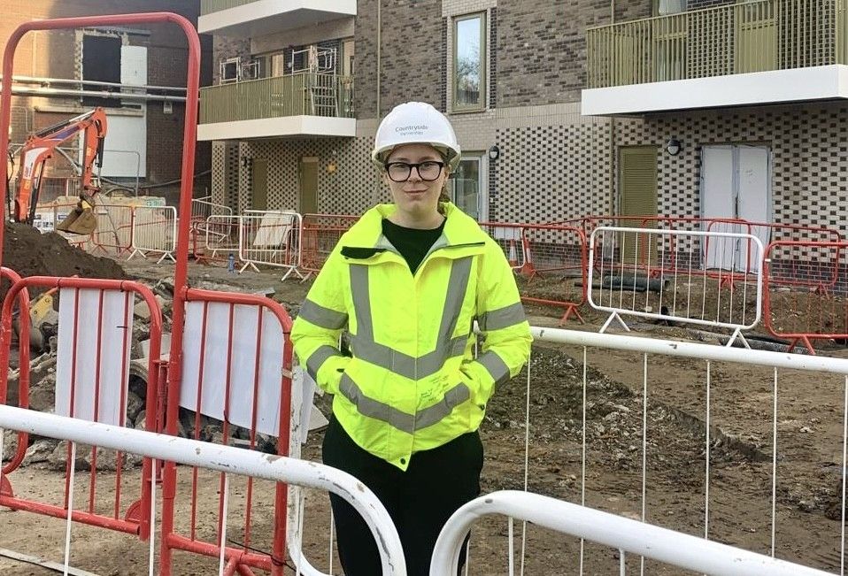 Construction student in hi-vis in front of construction site