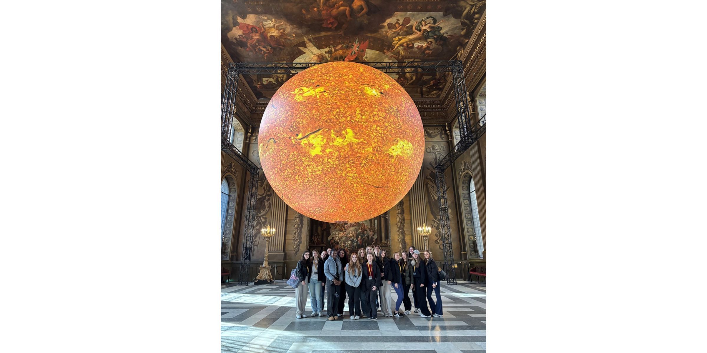 Students in grand room with orb hanging from ceiling