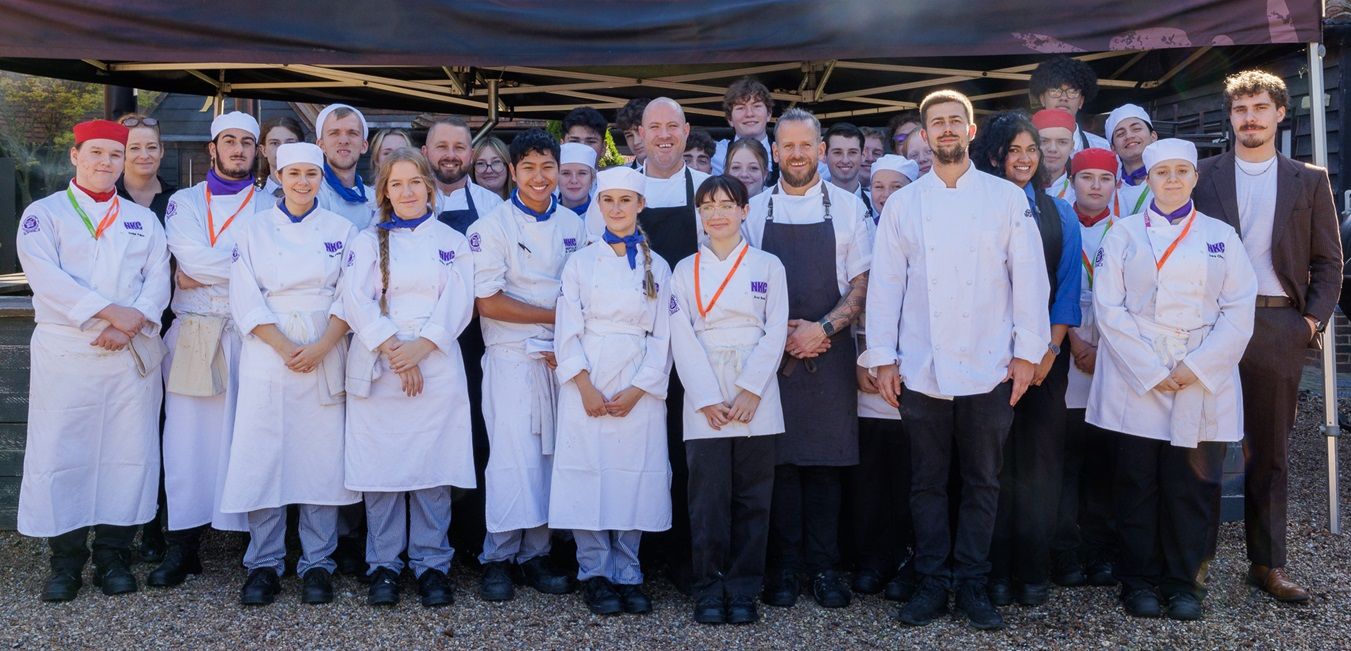 Group of students stood with chefs in marquee