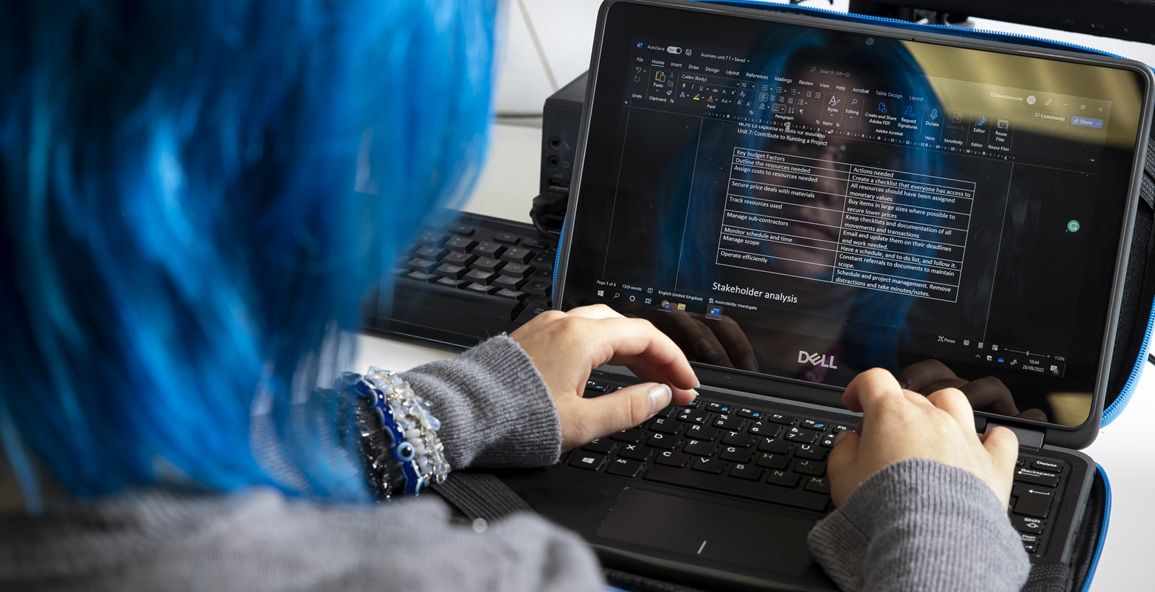 Young person typing on laptop computer. Screen visible.