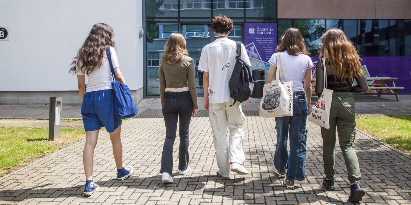 Four female students and one male student walking away from the camera