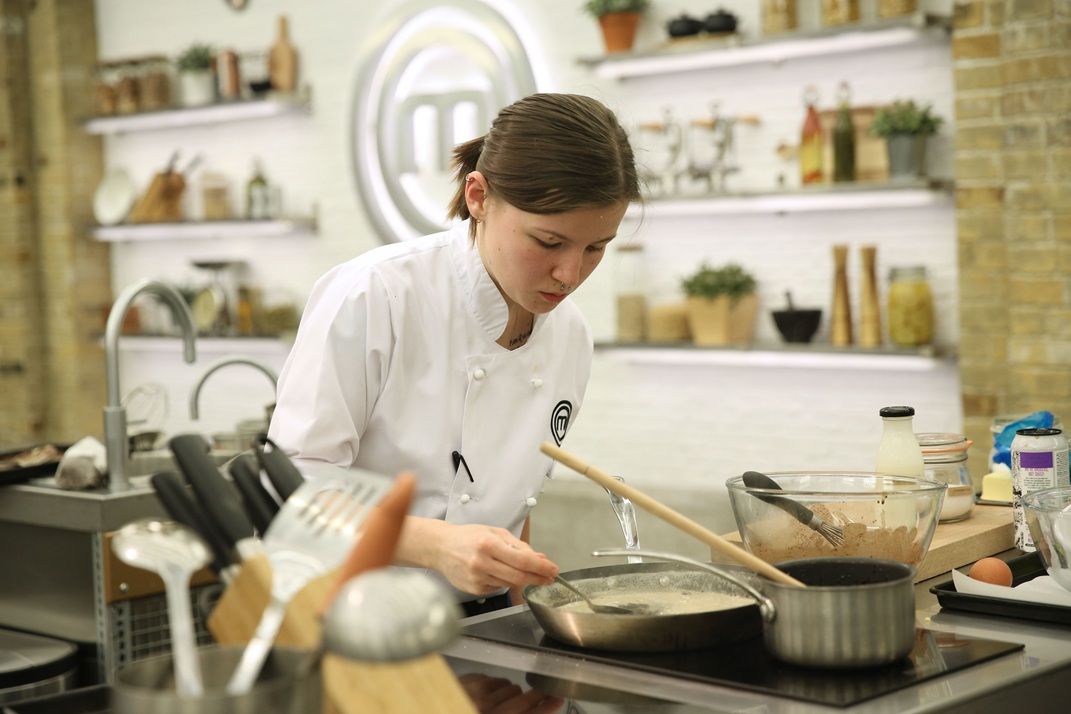 Young lady in kitchen in white chef's apron